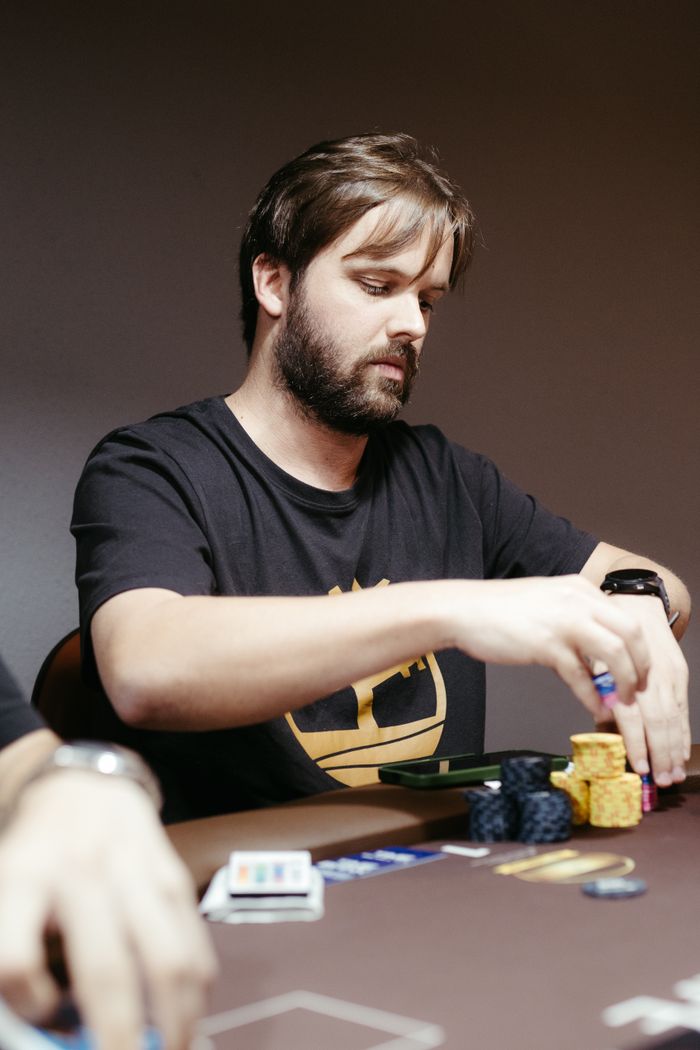 Man playing poker in a casino, organizing chips during the game night indoors.