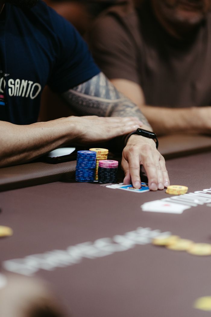 Close-up of a poker player organizing chips during a high-stakes game, displaying focus and strategy.