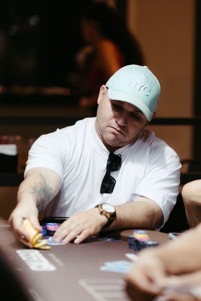 A focused poker player strategizes during an intense casino game. Indoor setting with poker chips and cards.